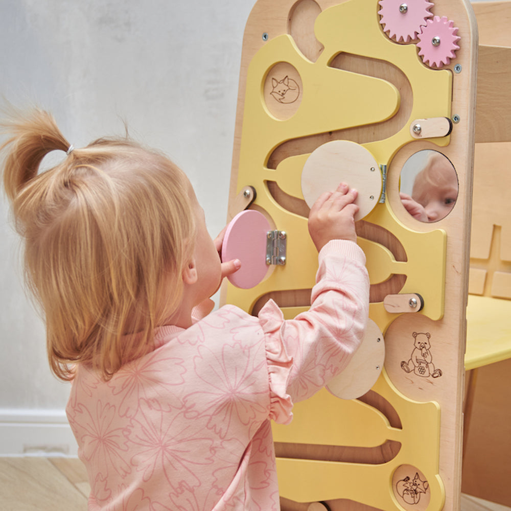 Toddler standing in a Montessori learning tower at the kitchen counter